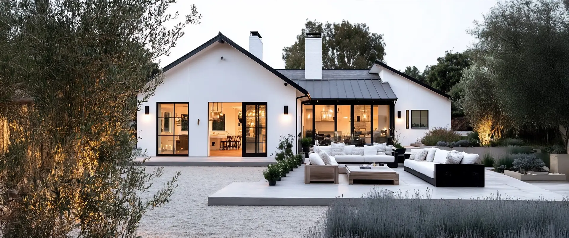Exterior view of a modern white house with black trim and outdoor patio furniture.
