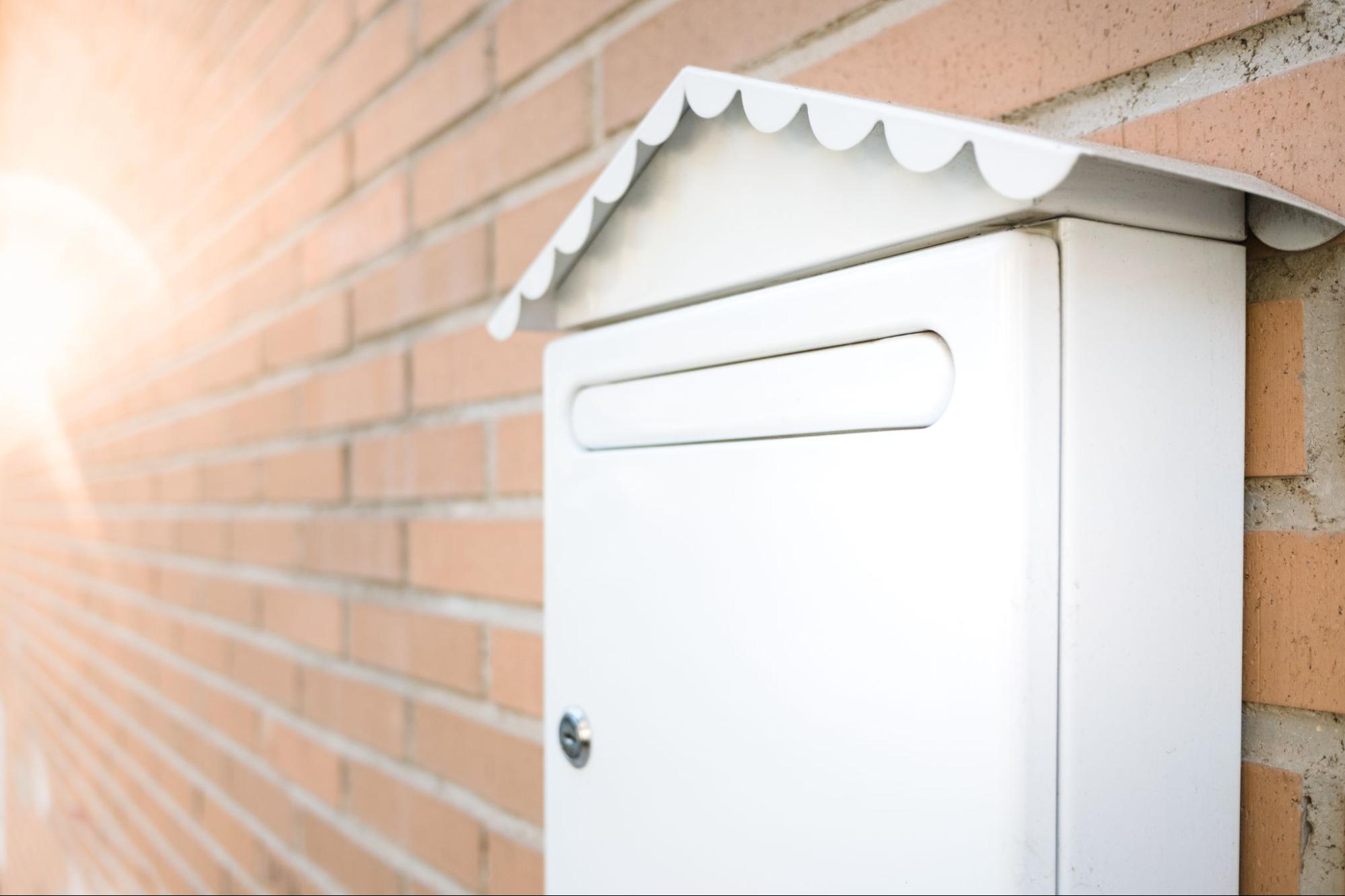A white mailbox on a brick wall.