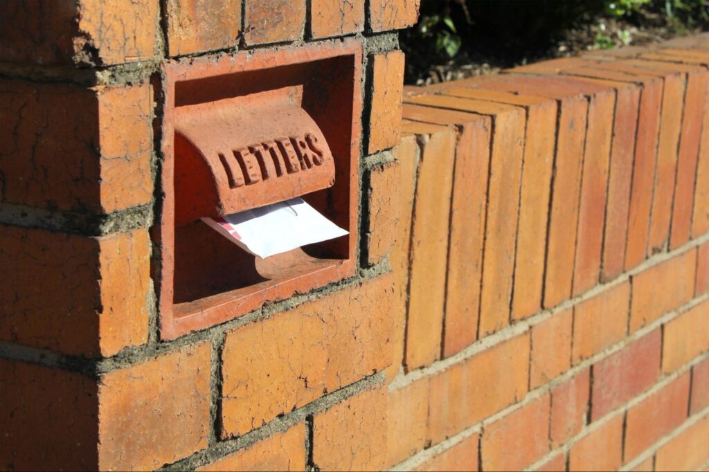 A vintage brick mailbox with a letter partially visible in the mail slot.