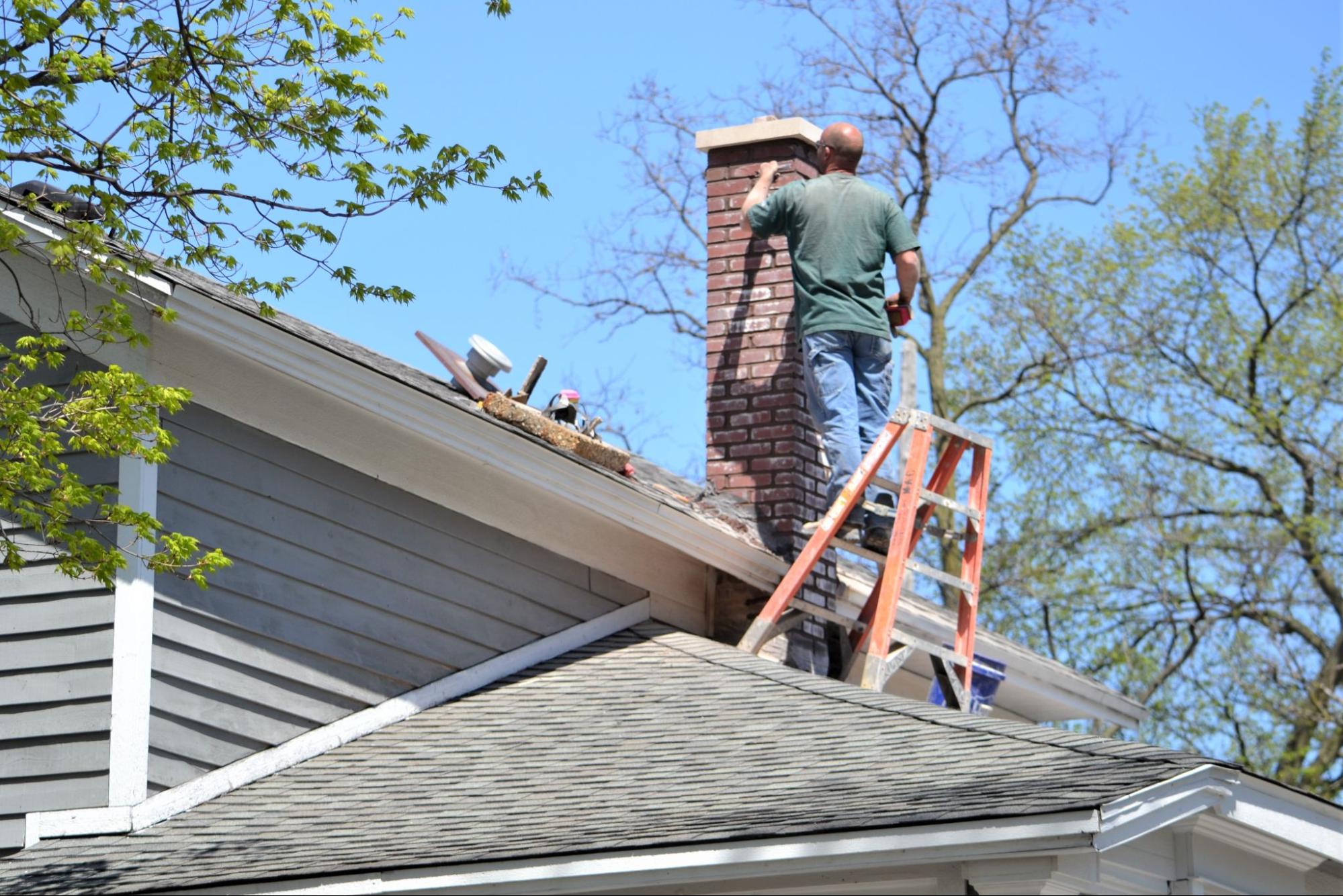 A man repairing the exterior brickwork of a chimney.