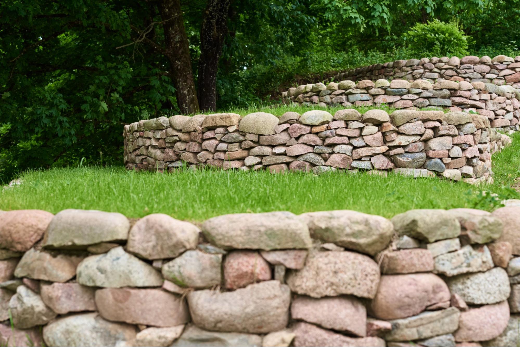 Tiered retaining walls made of multicolored, irregular stones.