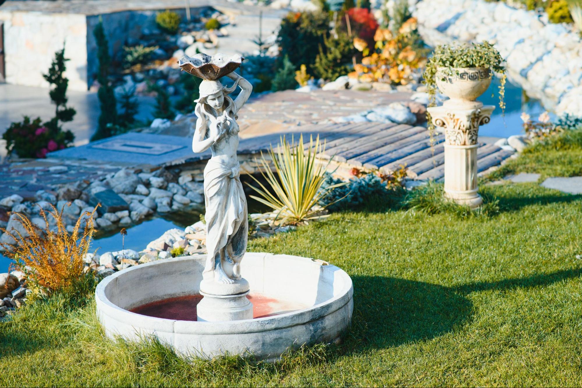 Decorative stone garden with lady sculpture and pillar vase.