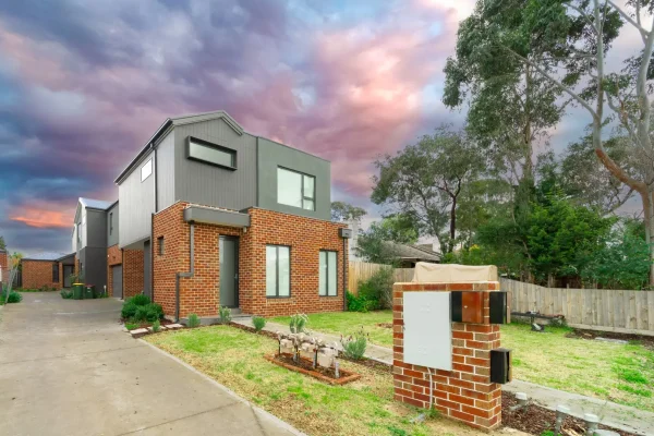 Two town houses covered in brick veneer. We see purple and orange hues as the sun sets in the background.