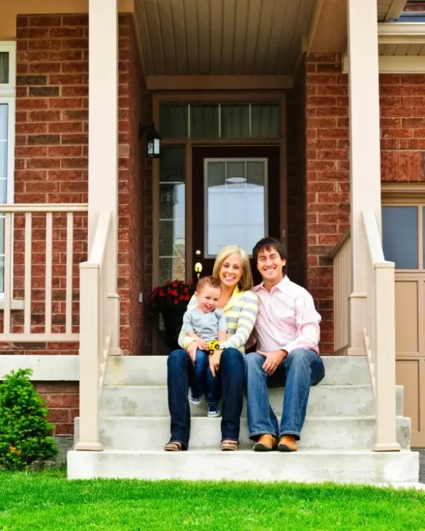 Happy family sitting on the stone steps in front of their brick home.