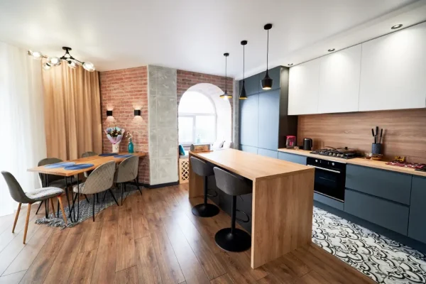 Loft style interior design studio apartment in gray and beige colors with wood and brick tuck pointing elements. Clearly and harmoniously separating kitchen and recreation areas.