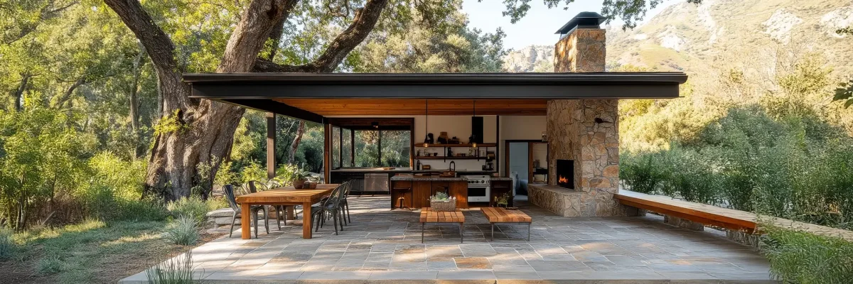 Traditional outdoor living space featuring an open-air kitchen, fireplace, and dining area with natural stone pavers.